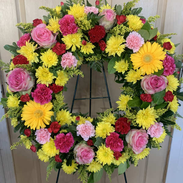 Circular wreath of pink, yellow, and red flowers on a stand
