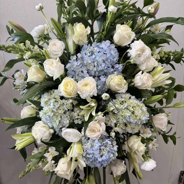 Large standing floral spray with white roses, lilies, and blue hydrangeas