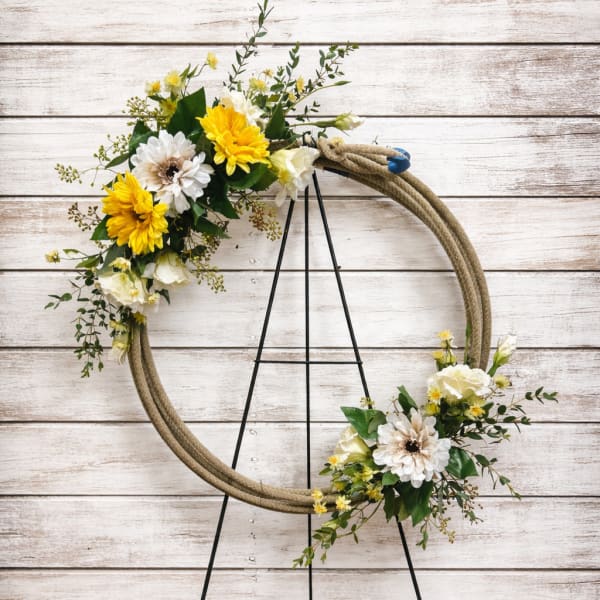 Floral wreath with yellow and white flowers on a black stand