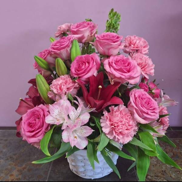 Pink roses and lilies arranged in a white basket