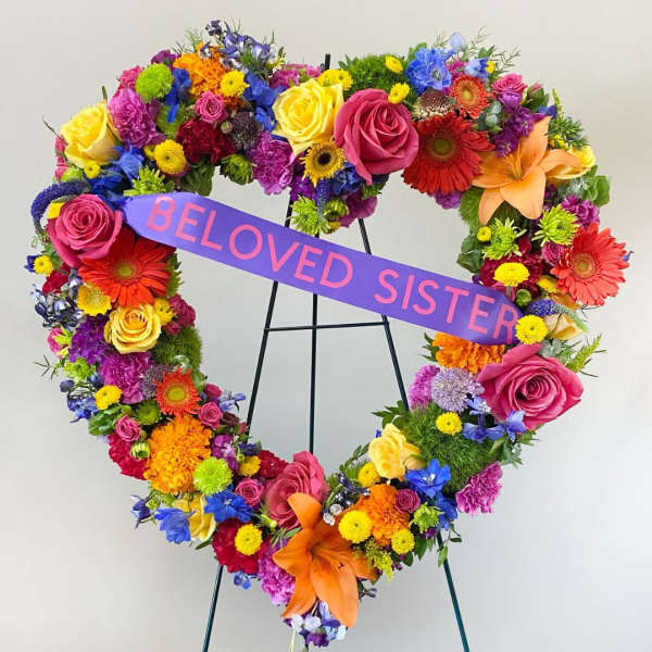 Heart-shaped floral wreath with a purple ribbon reading "BELOVED SISTER"