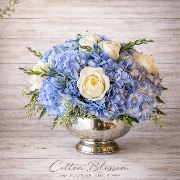 Blue hydrangea and white rose arrangement in a silver vase