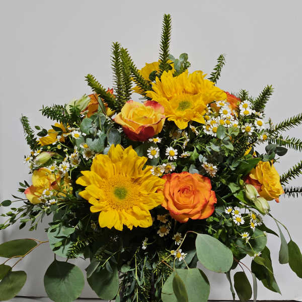 Bouquet of yellow sunflowers and orange roses in a glass vase
