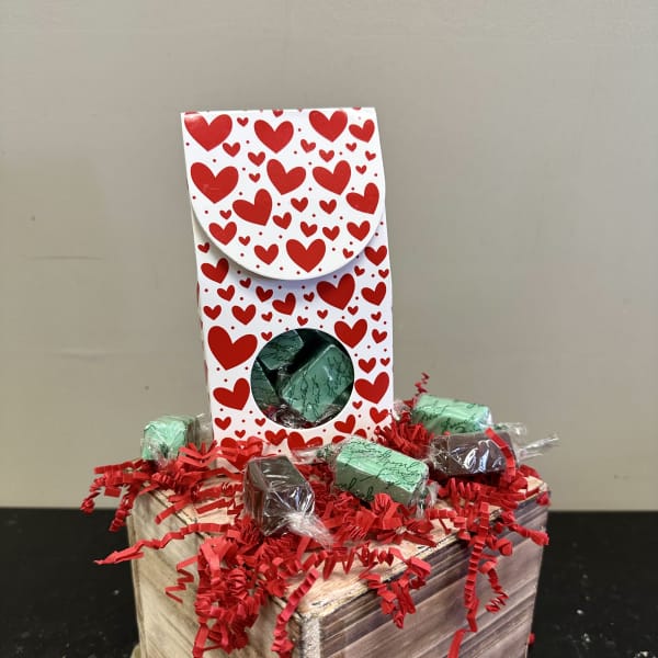 Heart-patterned gift box with wrapped chocolates on a wooden crate