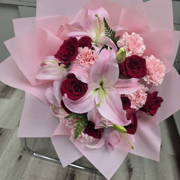 Pink lily and red rose bouquet wrapped in pale pink paper