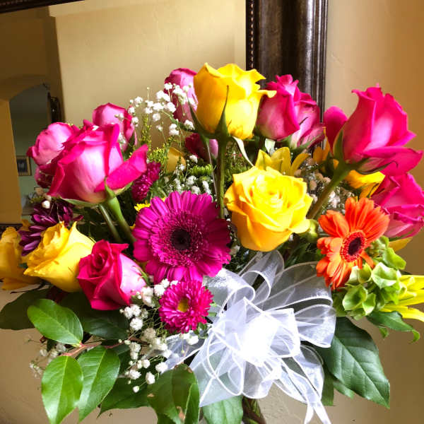 Bouquet of pink and yellow roses with gerbera daisies in a glass vase