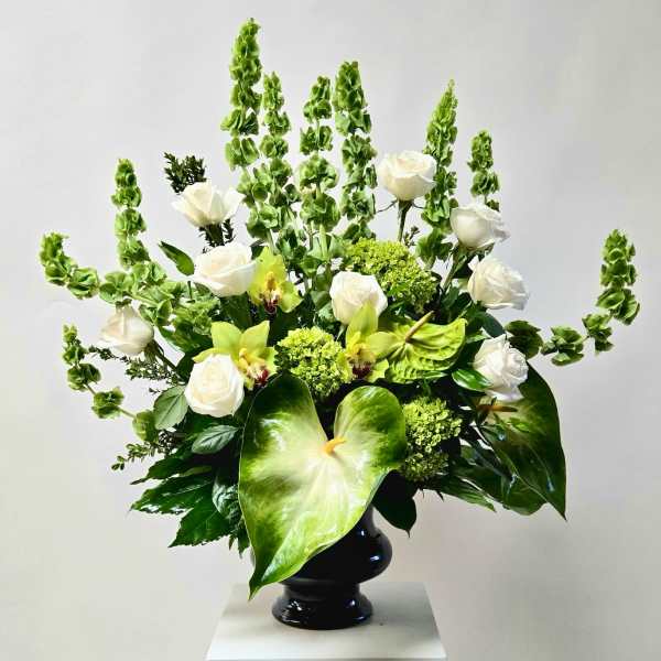 White roses and green orchids in a black vase