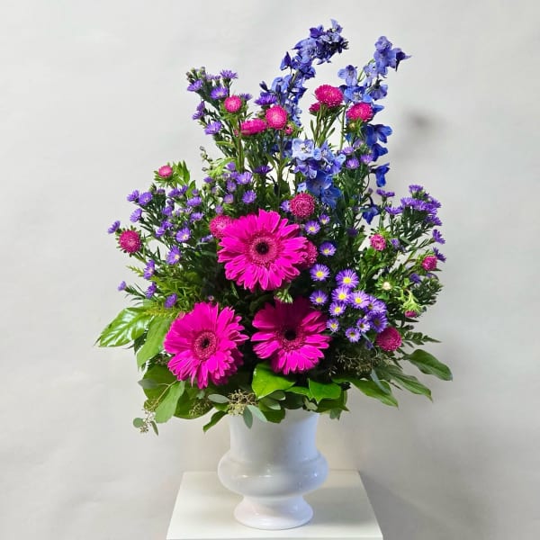 Pink and purple mixed flowers arranged in a white vase