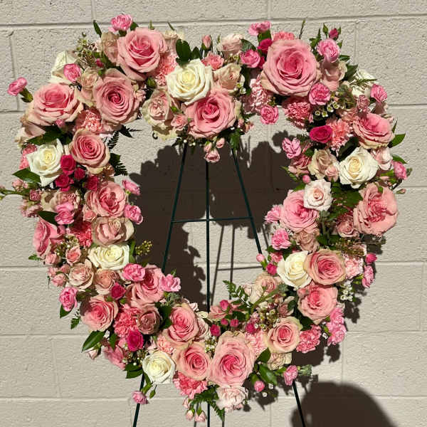 Heart-shaped floral wreath of pink and white roses on a stand