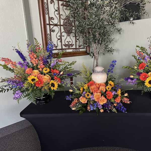 Three colorful floral arrangements on a black-draped table