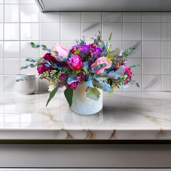 Mixed pink and purple flower arrangement in a white vase