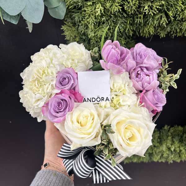 Heart-shaped bouquet of white, pink, and lavender roses with a striped ribbon