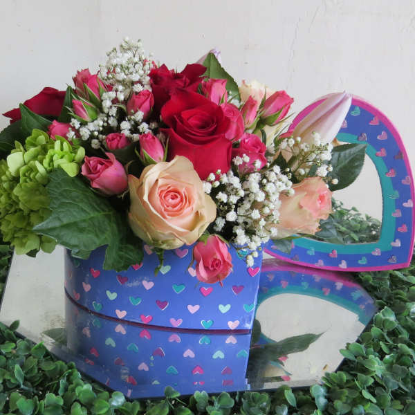 Heart-shaped box filled with roses and mixed flowers