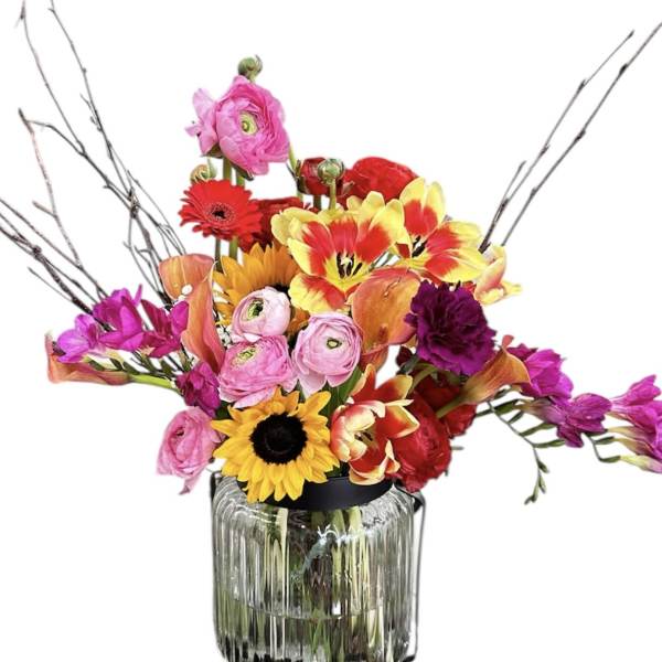 Mixed bouquet in a glass vase with bright pink, red, yellow, and purple flowers