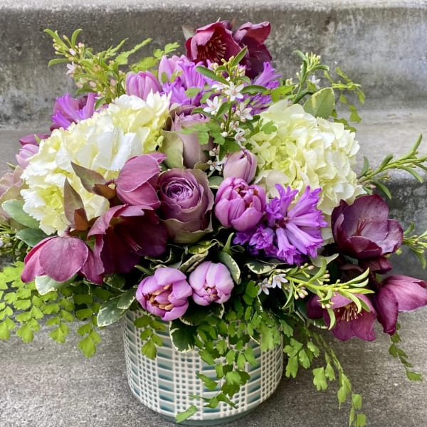 Purple and white floral arrangement in a patterned ceramic vase