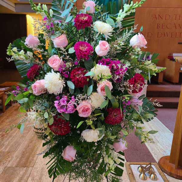 Large pink and white floral arrangement on a stand