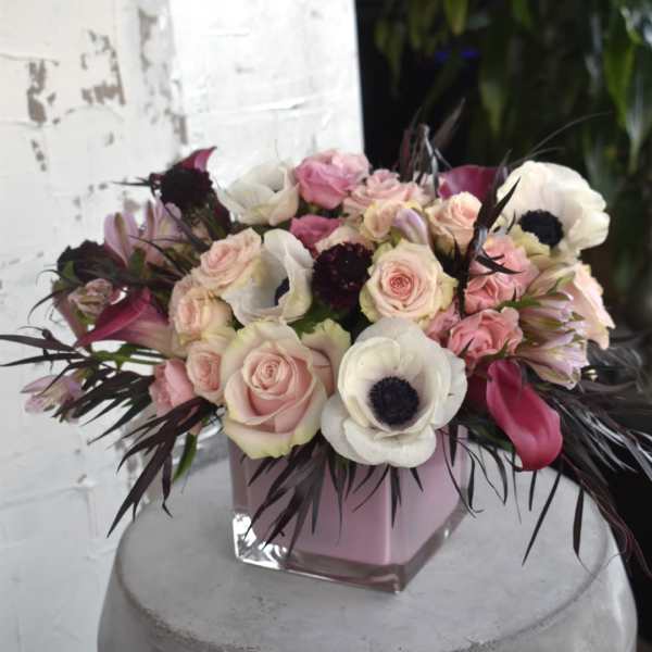 Pink and white floral arrangement in a square glass vase