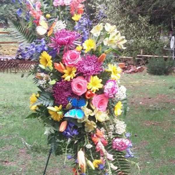 Tall standing floral spray with mixed bright flowers on a metal easel