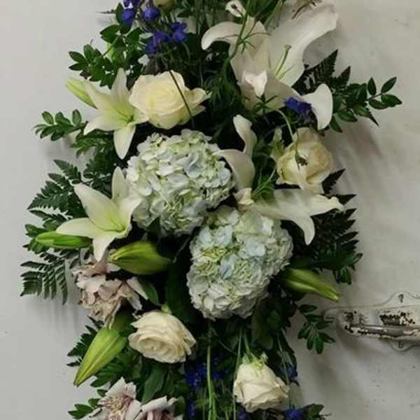 Tall floral spray with white lilies, roses, blue delphinium, and hydrangeas