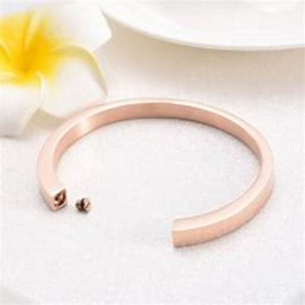 Rose gold open cuff bracelet beside a white flower