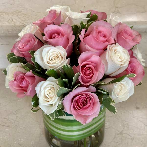 Pink and white roses arranged in a glass vase
