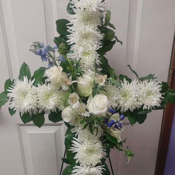 White floral cross on a stand with roses and chrysanthemums