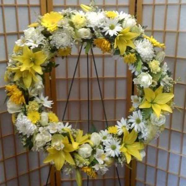 Yellow and white floral wreath on a stand