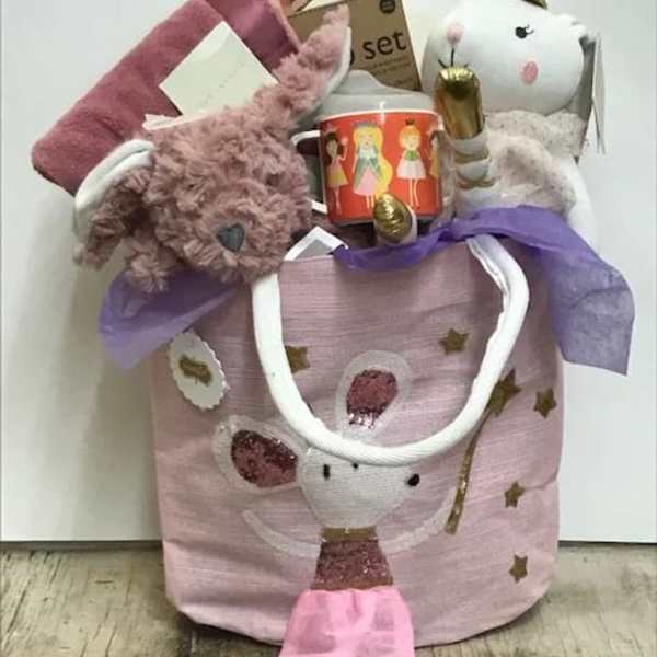Pink gift basket with a plush bunny, mug, and small wrapped items