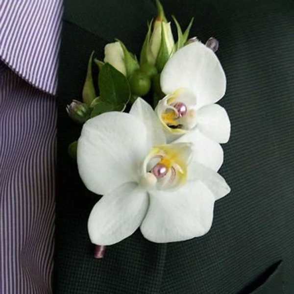 White orchid boutonniere pinned to a dark suit jacket