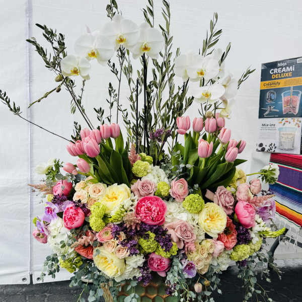 Large floral arrangement with white orchids, pink tulips, and mixed roses in a decorative vase
