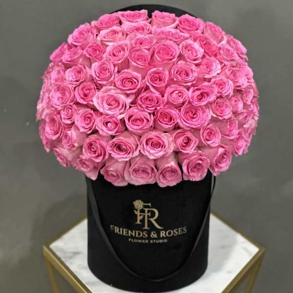 Round bouquet of bright pink roses in a black hat box