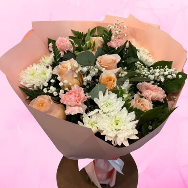 Bouquet of peach roses, white chrysanthemums, and pink carnations in pink wrap