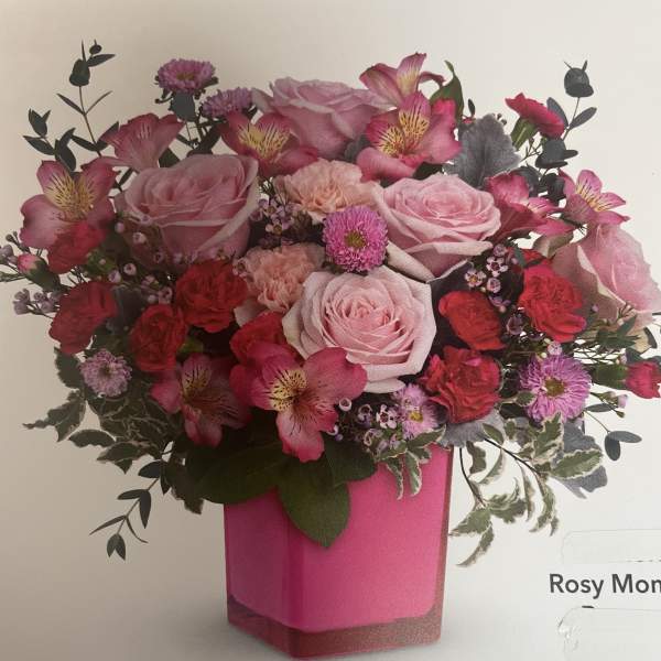 Pink roses and mixed blooms arranged in a bright pink vase