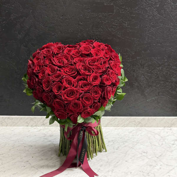 Heart-shaped bouquet of red roses with a ribbon tie