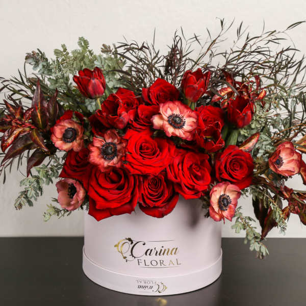 Red roses and pink anemones in a white hatbox