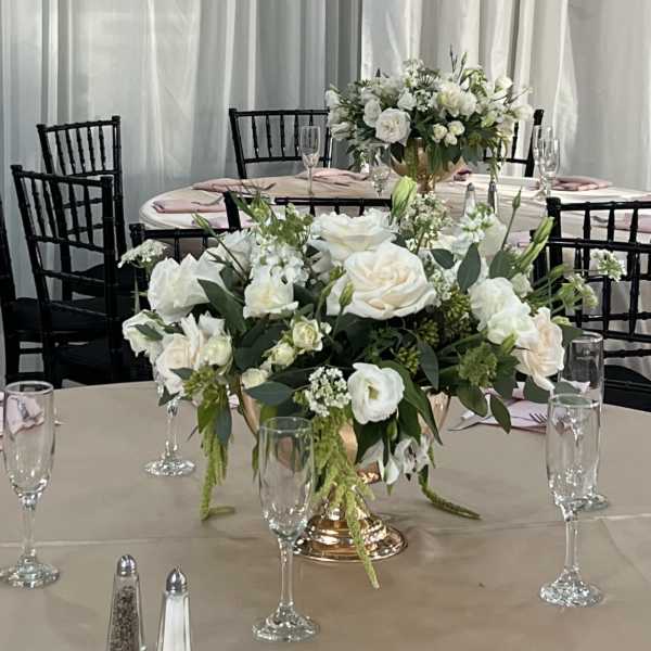 White floral centerpieces on round banquet tables with pink napkins