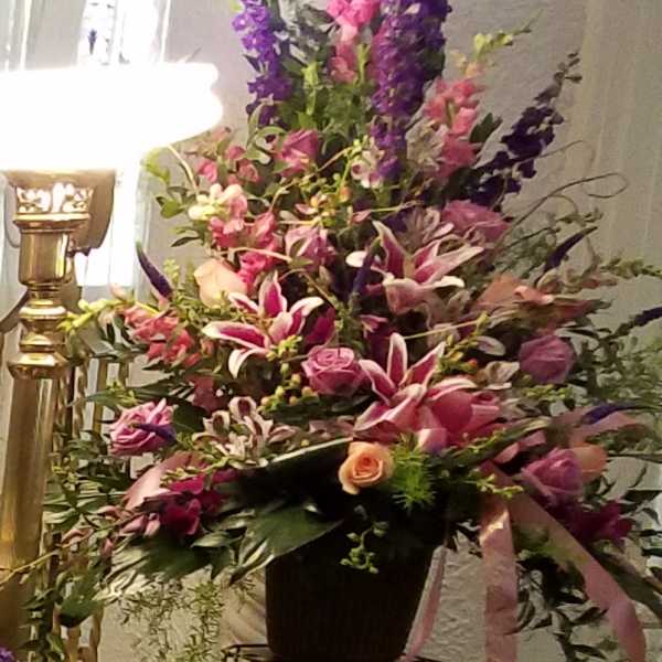 Tall floral arrangement in a black container with pink, purple, and white blooms