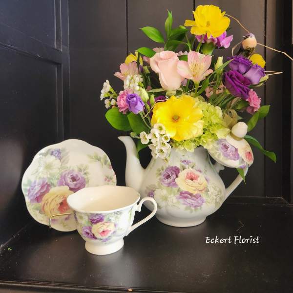 Floral arrangement in a floral teapot with matching teacup and saucer