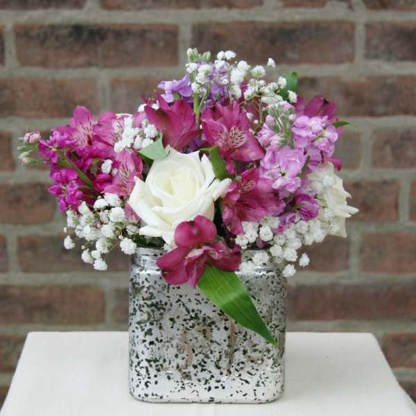 Pink and white flower arrangement in a silver square vase