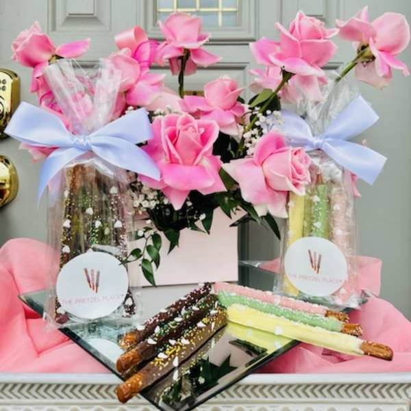 Pink roses in gift bags with chocolate-covered pretzel rods on a tray