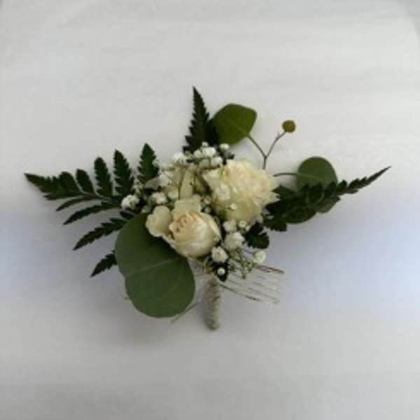 White floral boutonniere with greenery on a white background