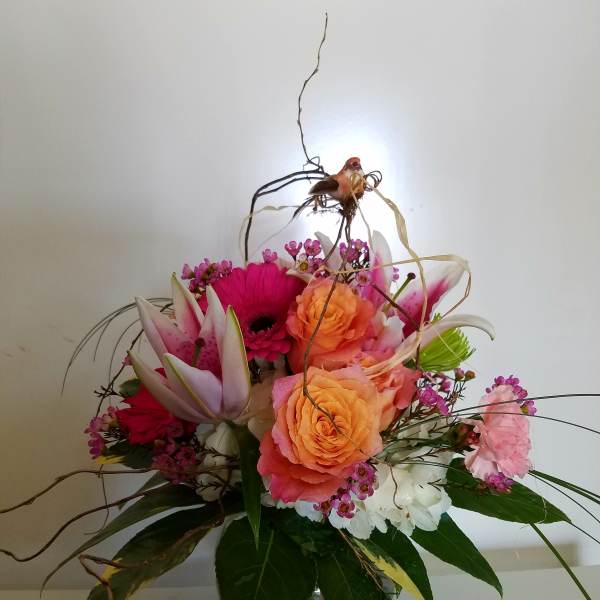 Mixed bouquet of pink and orange flowers in a glass vase