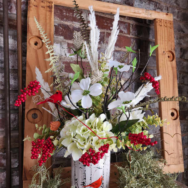 White floral arrangement in a birch-print container with red berry accents