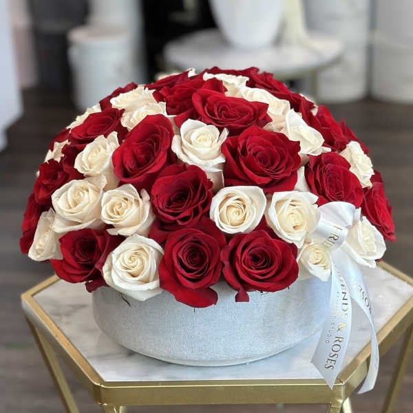 Round box arrangement of red and white roses with a ribbon