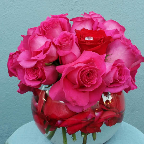 Pink and red roses arranged in a round glass vase