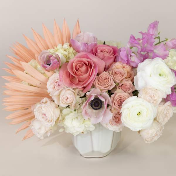 Pink and white floral arrangement in a white vase with peach accents