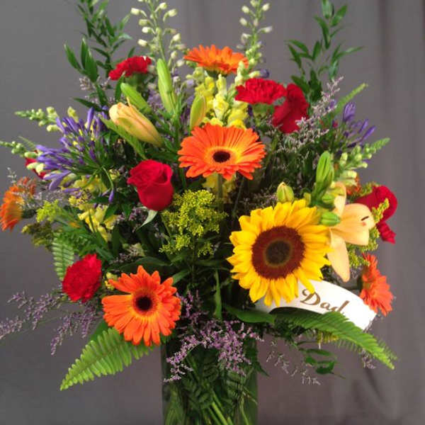 Colorful mixed bouquet in a glass vase with a "Dad" ribbon