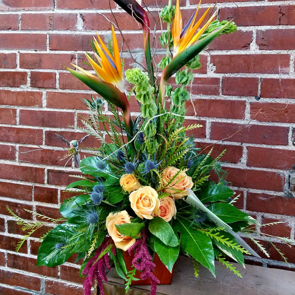 Tropical flower arrangement with orange roses and bird-of-paradise blooms
