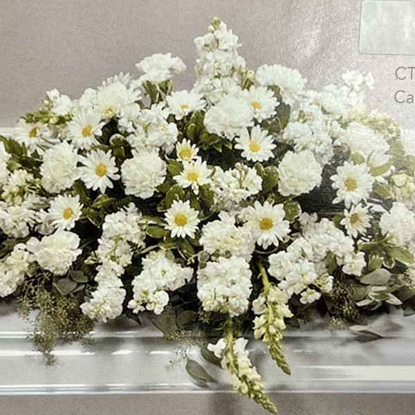 Long white casket spray of daisies and carnations with cascading blooms.