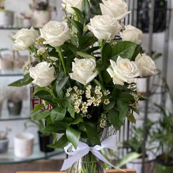 Bouquet of white roses in a clear glass vase with a white ribbon